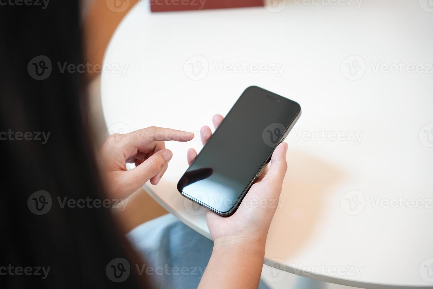 a person holding a black smartphone on a table photo