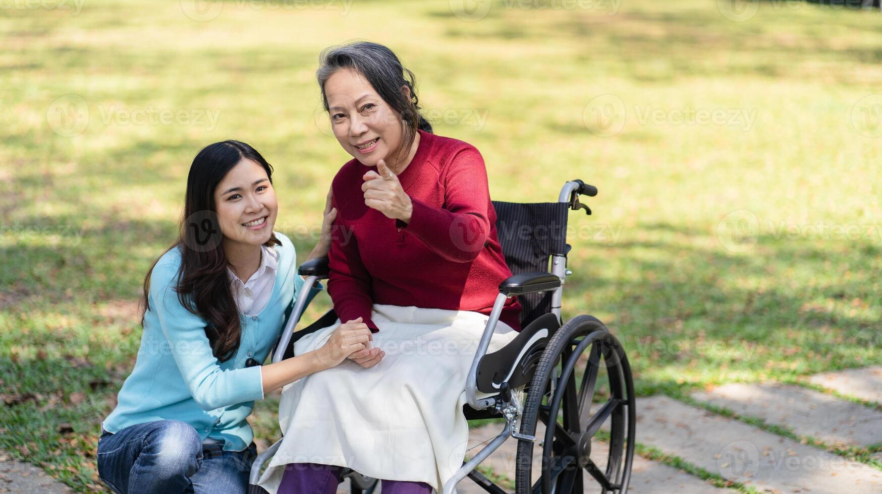 Asian senior woman in wheelchair with happy daughter. Family relationship retired woman sitting on wheelchair in the park age care at retirement photo