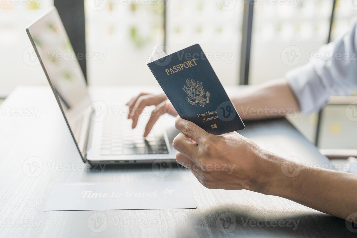 Hand Man Online booking and buying plane tickets using laptop phone and credit card Planning trip travel vacation with passport photo