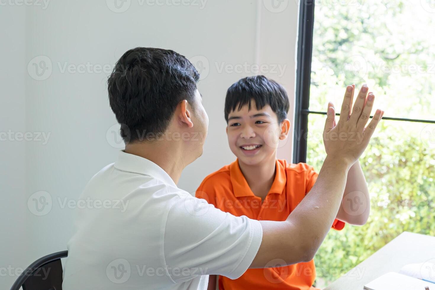 a man and boy sitting at a table with their hands up photo