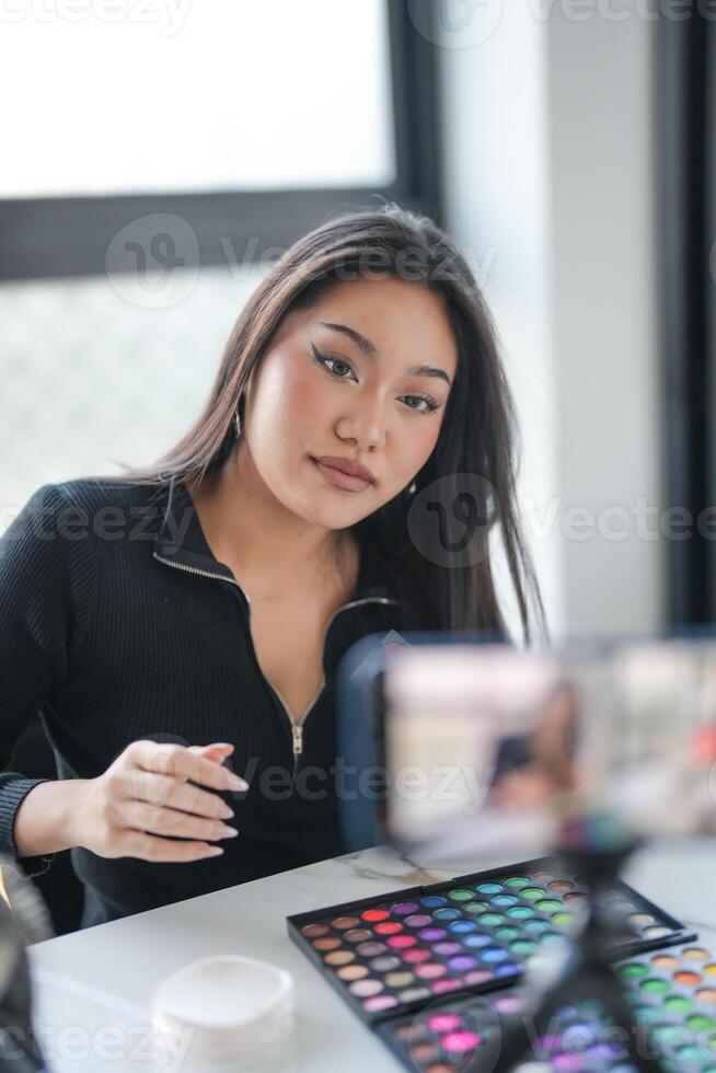 a woman sitting at a desk with a camera and makeup. photo
