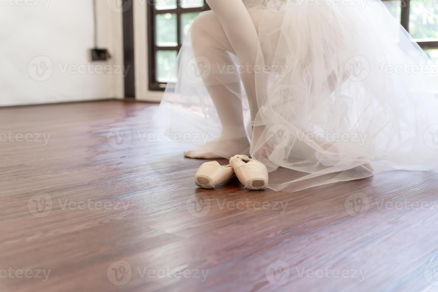 Ballerina in ballet shoes. Asian girl tying ribbons of toe shoes. ballet dancer preparing and wearing ballet shoes in dance studio prepares for a rehearsal. photo