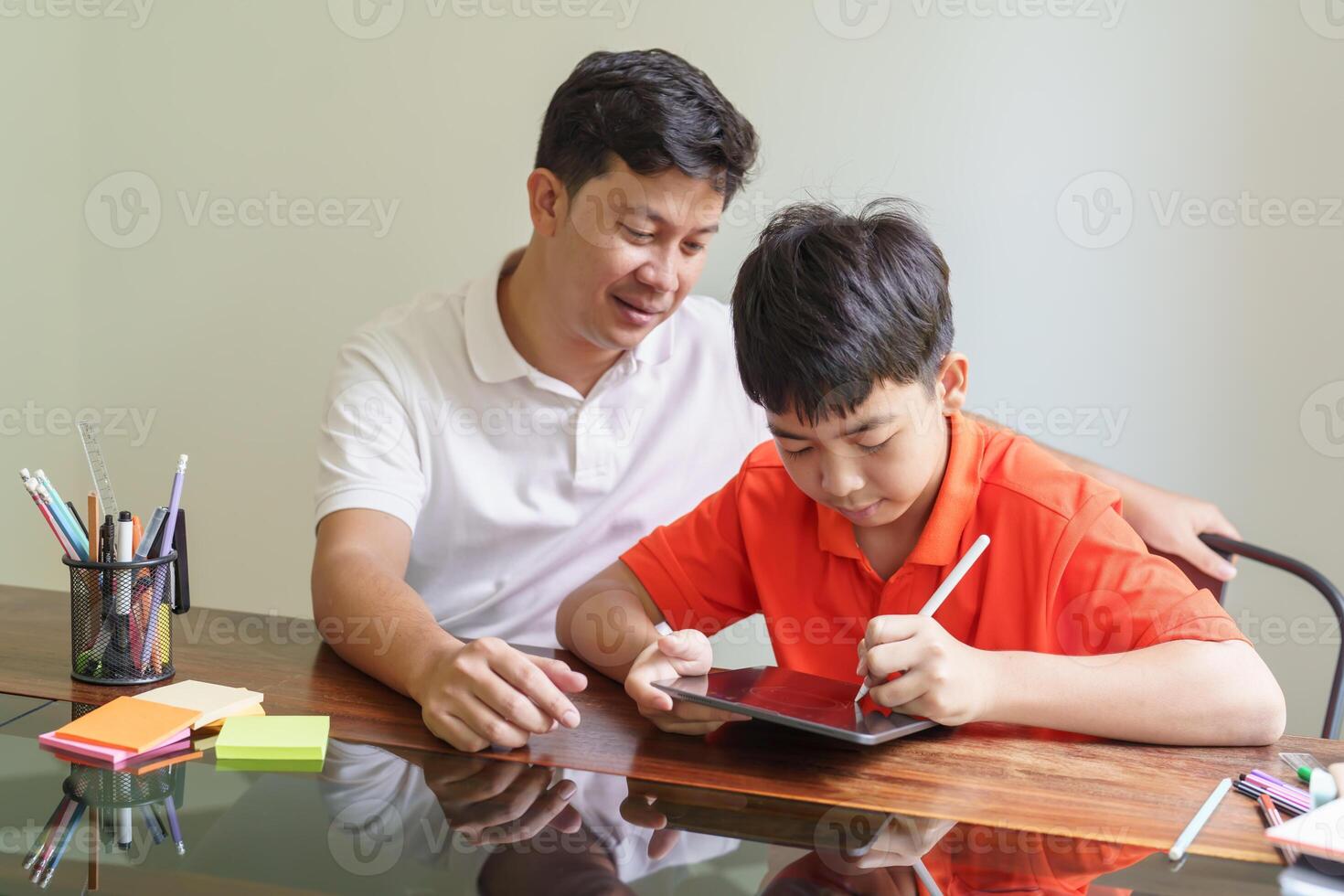 Asian father and son using tablet teaching son to drawplaying with digital tablet at desk fatherhood photo
