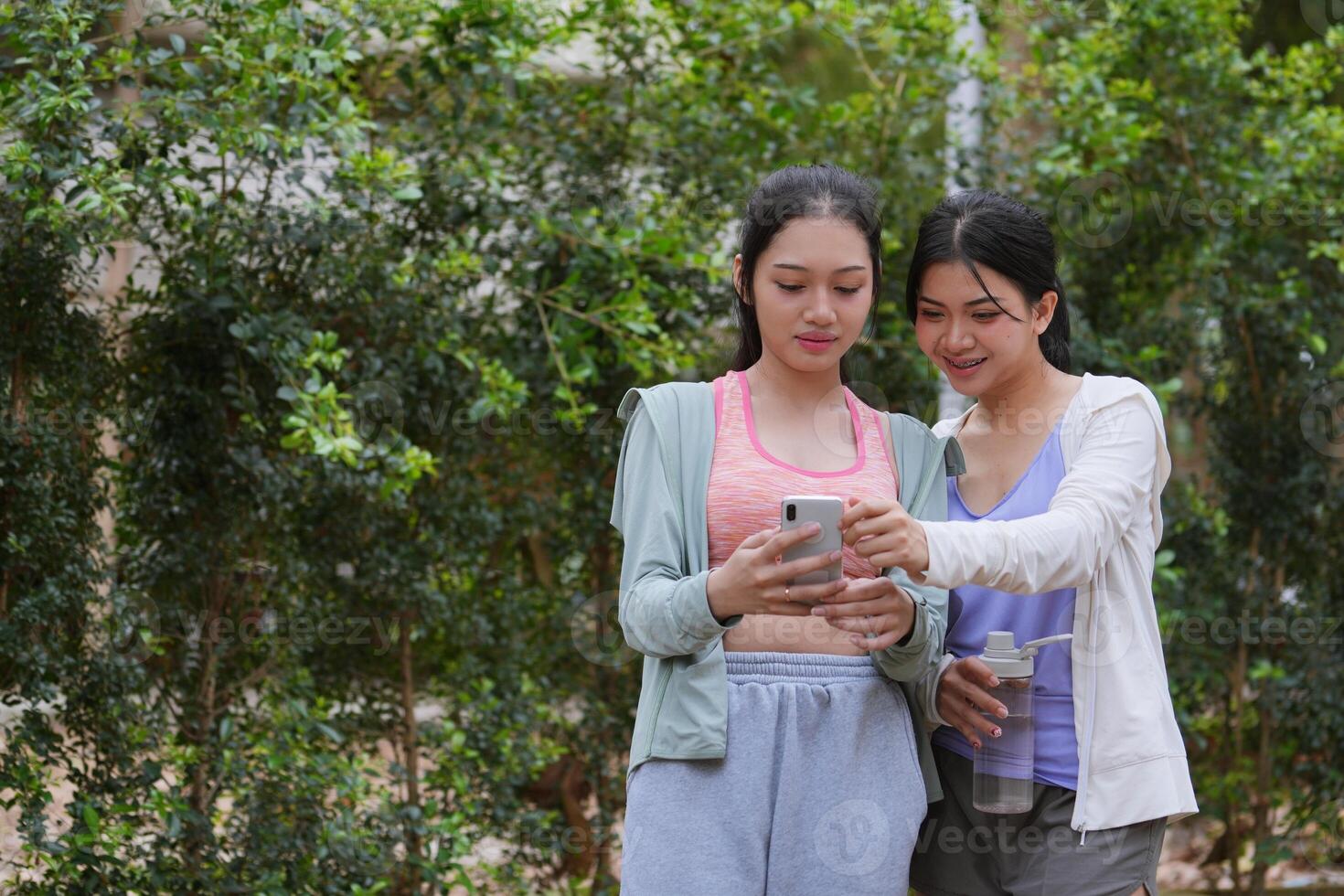 Asian women friends use phone after exercise and happy in Outdoor park photo