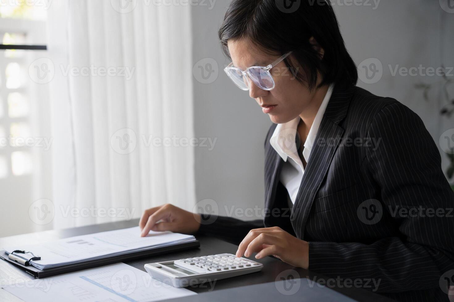 Middle age Asian woman Auditor or internal revenue service staff senior business woman checking annual financial elderly woman pressing calculator. photo