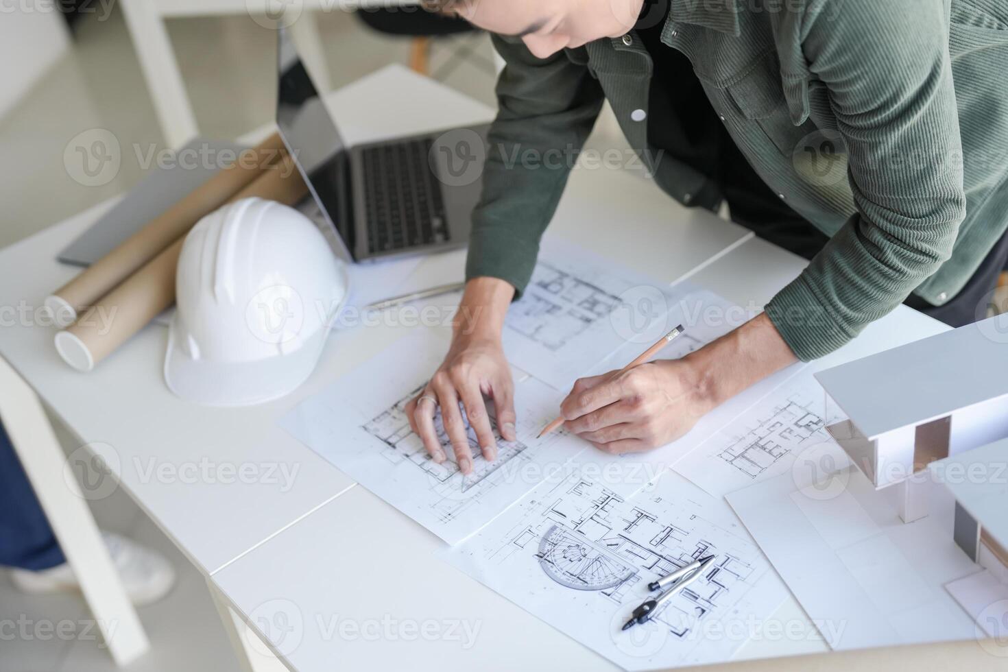 a man is working on a blueprint with a hardhat photo