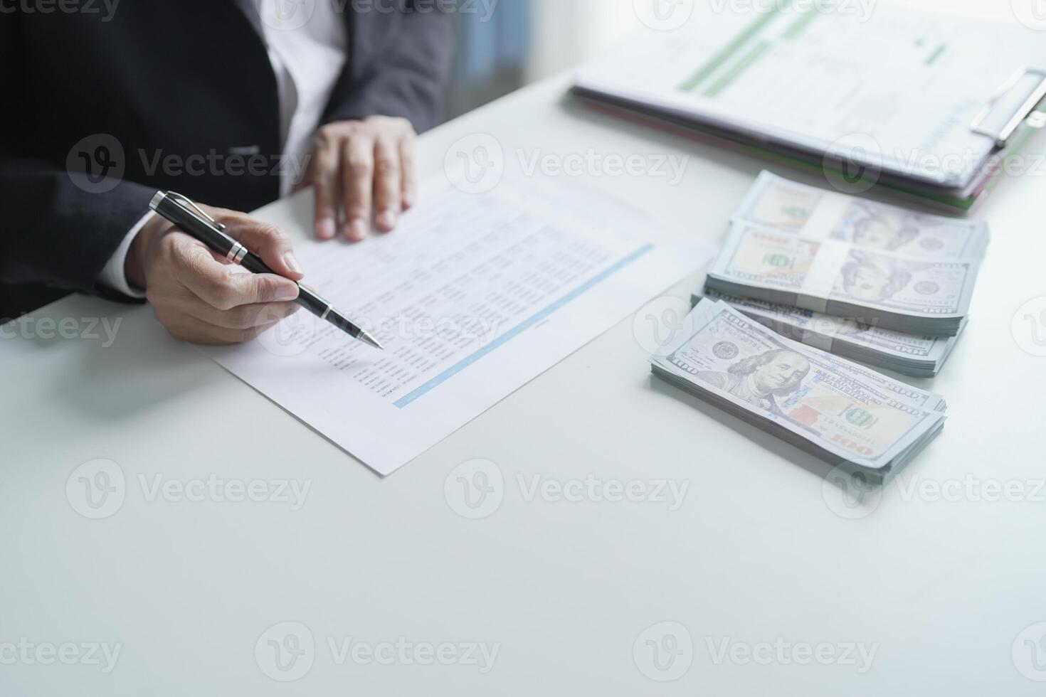 businessman signing documents with money on table photo