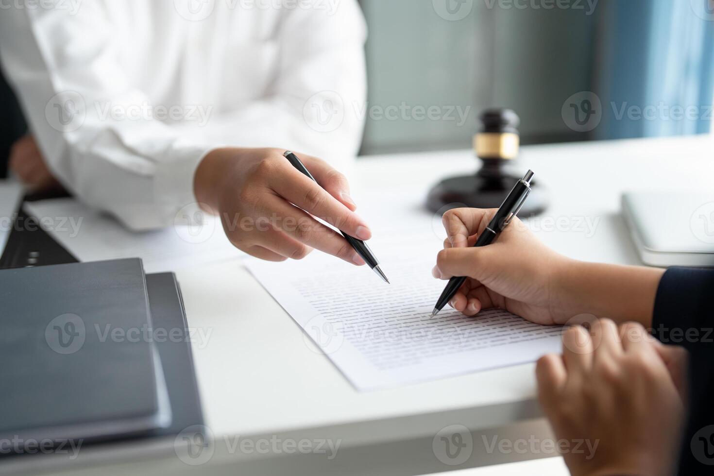 a man signing a document with a pen and a woman signing a document photo
