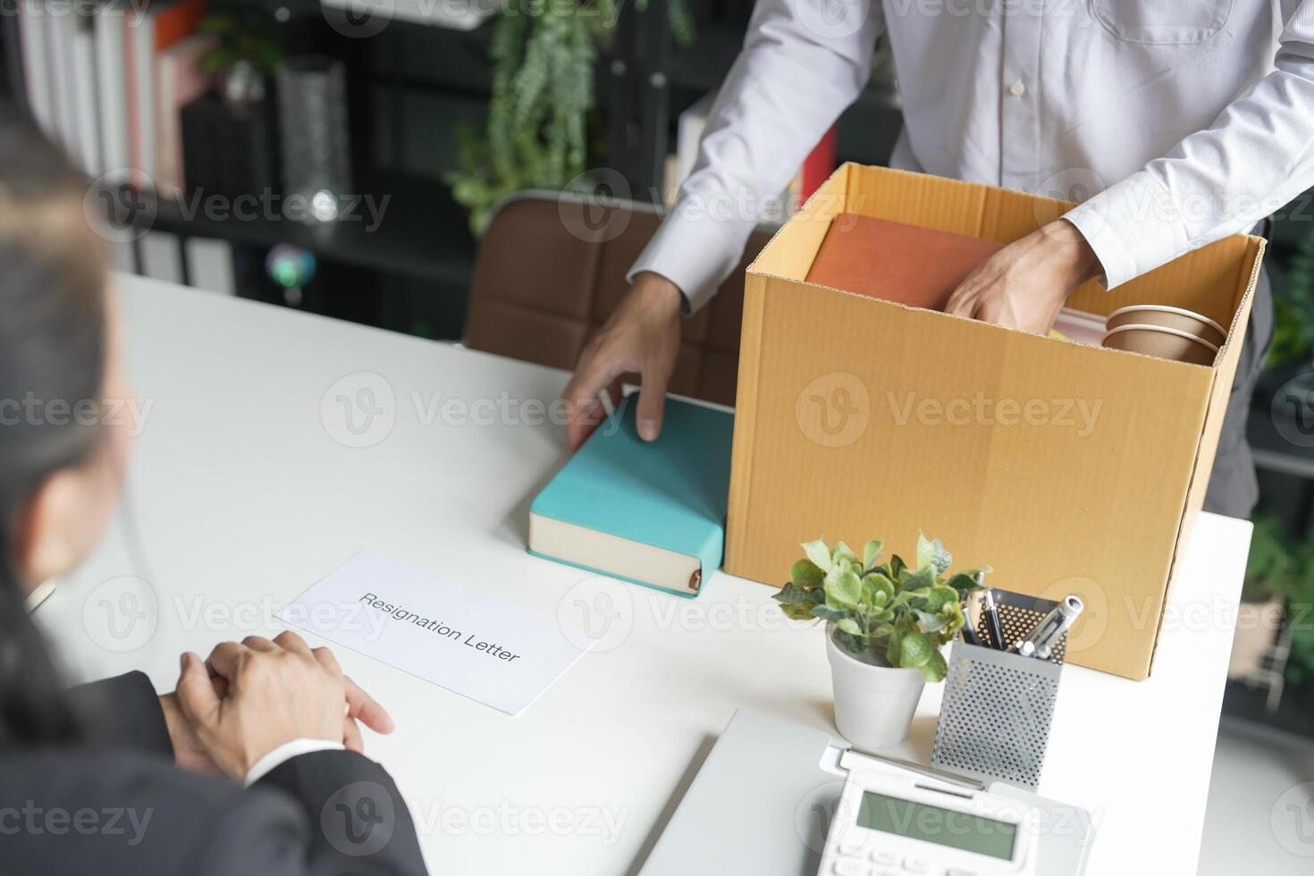 a man is opening a box with papers and a woman is sitting at a desk. photo