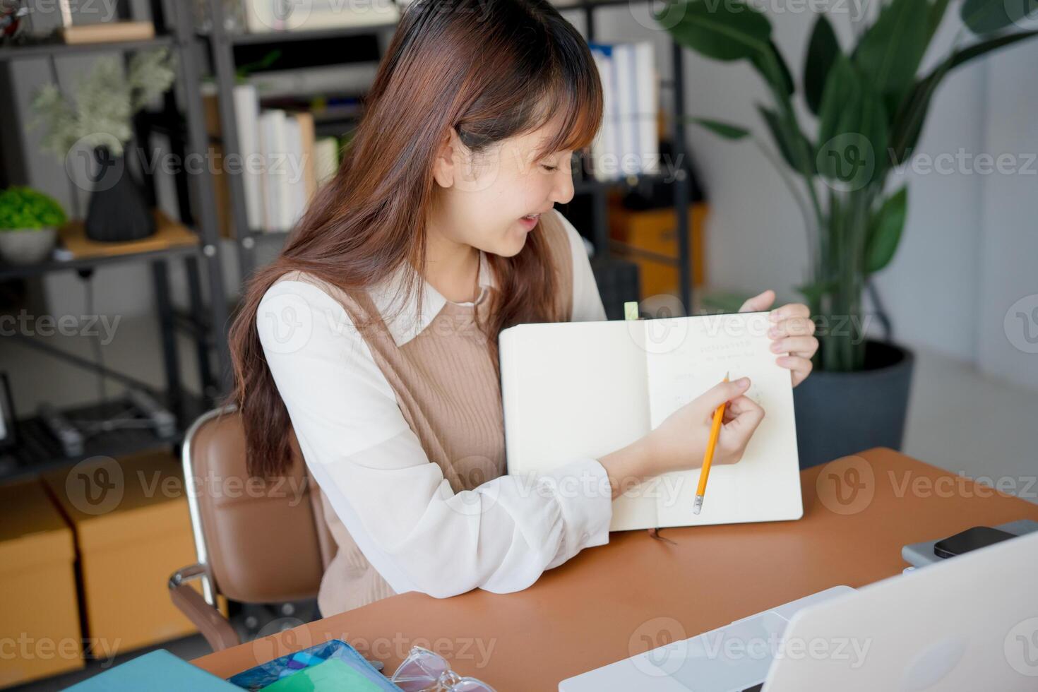 a woman is sitting at a desk with a notebook and a pen photo