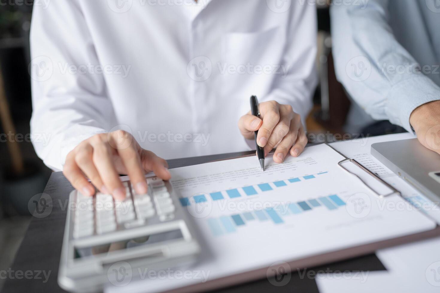businessman using calculator and pen to calculate the profit of a business photo