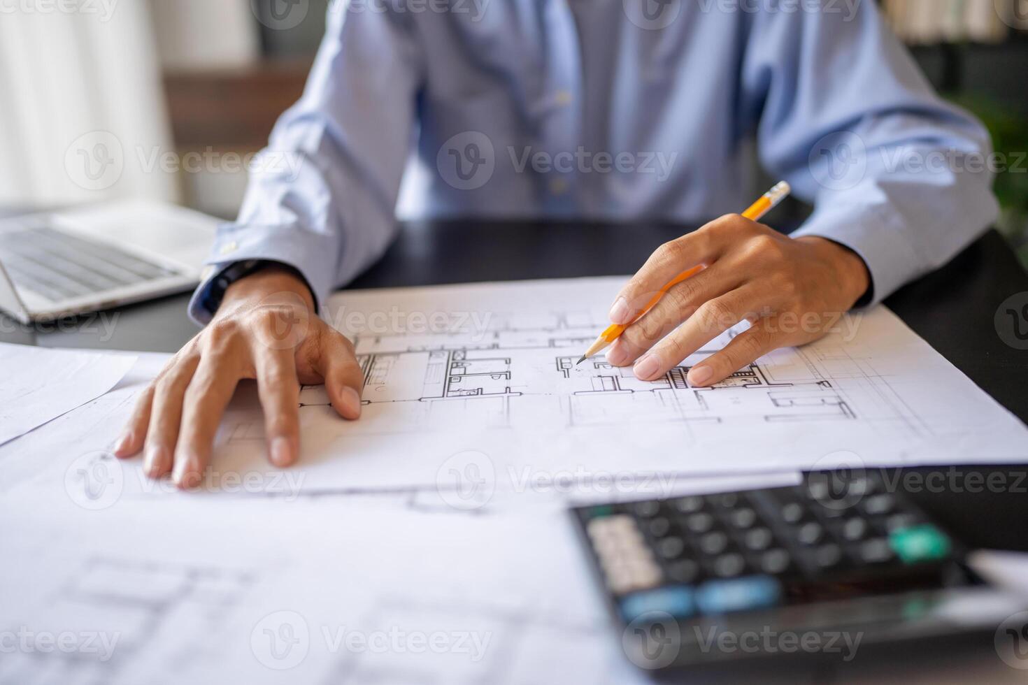 a person is working on blueprints with a calculator and pen photo