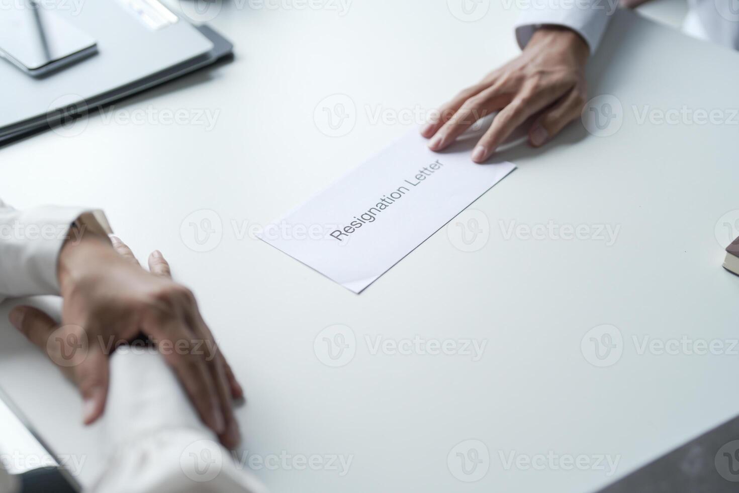 two people holding hands over a paper with a resignation letter photo