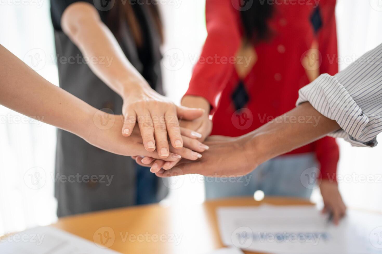Team building group of people Asian business hands stack unity and support Team fold theirs hands on each other. photo