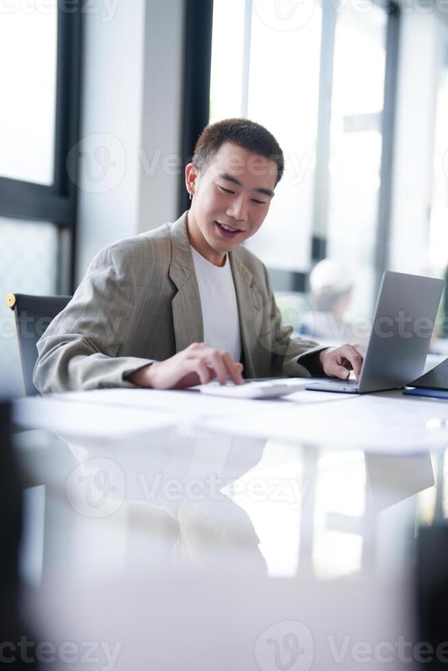 Attractive confident millennial, Asian Business man using laptop computer and professional working investor start up project business planning in office. photo