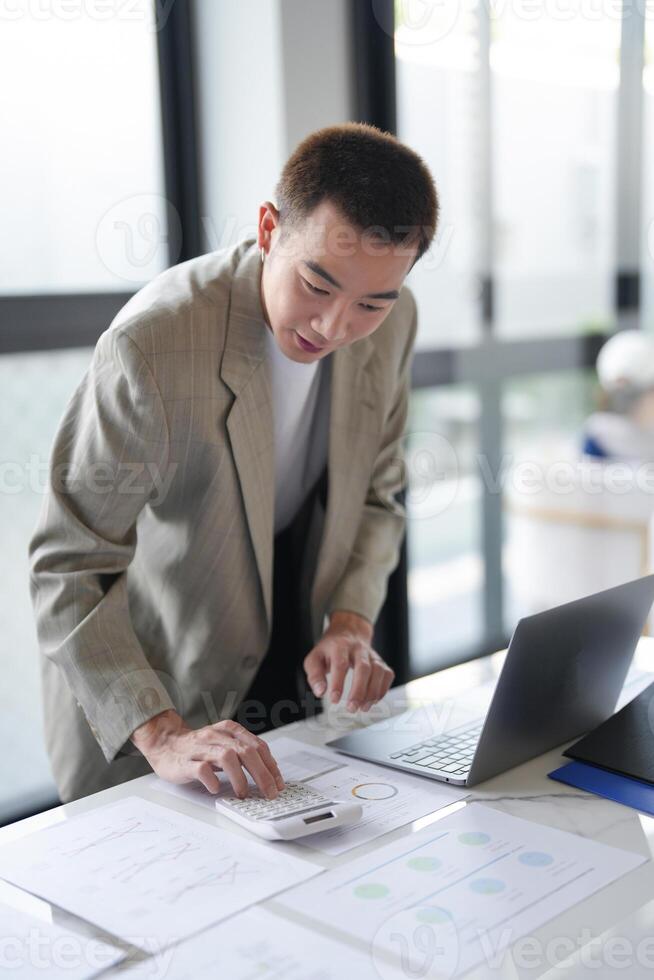 Attractive confident millennial Asian Business man using laptop computer and professional working start up project business planning in office. photo