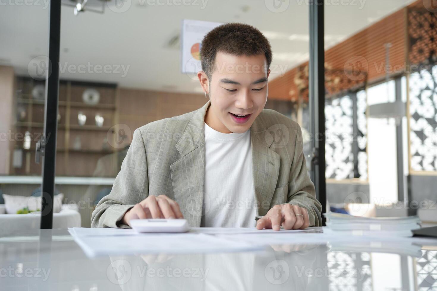 asian man in suit sitting at table with calculator photo