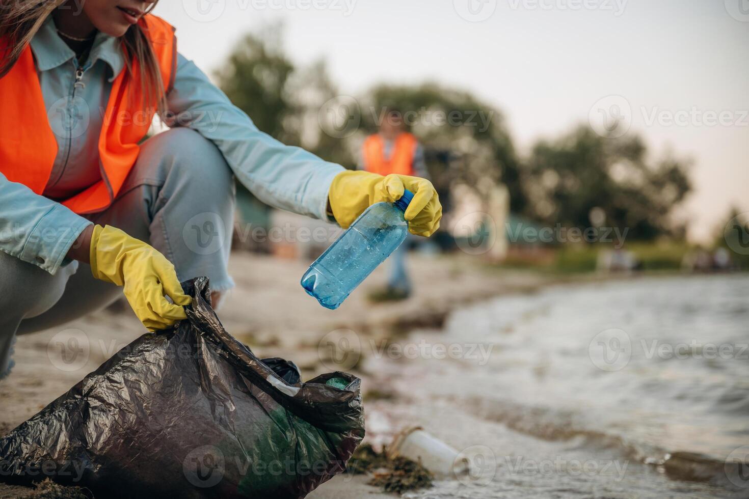 On ,the ,,,shore. A volunteers collects garbage on a muddy beach photo