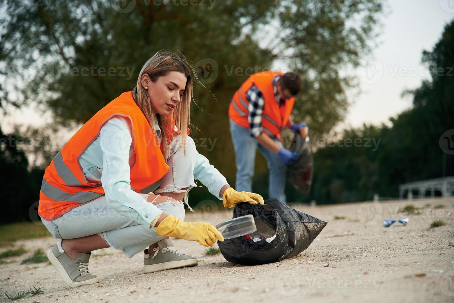Picking ,up the bottle. A volunteers ,collects garbage on a muddy beach photo