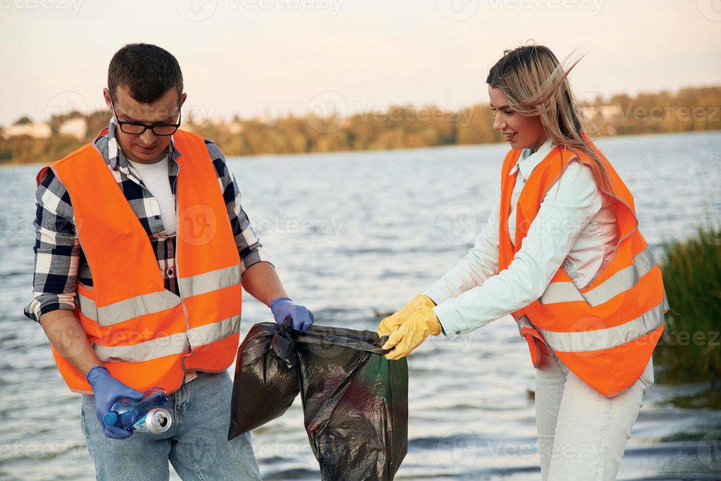 With trash bags. A, volunteers, collects garbage on a muddy beach photo