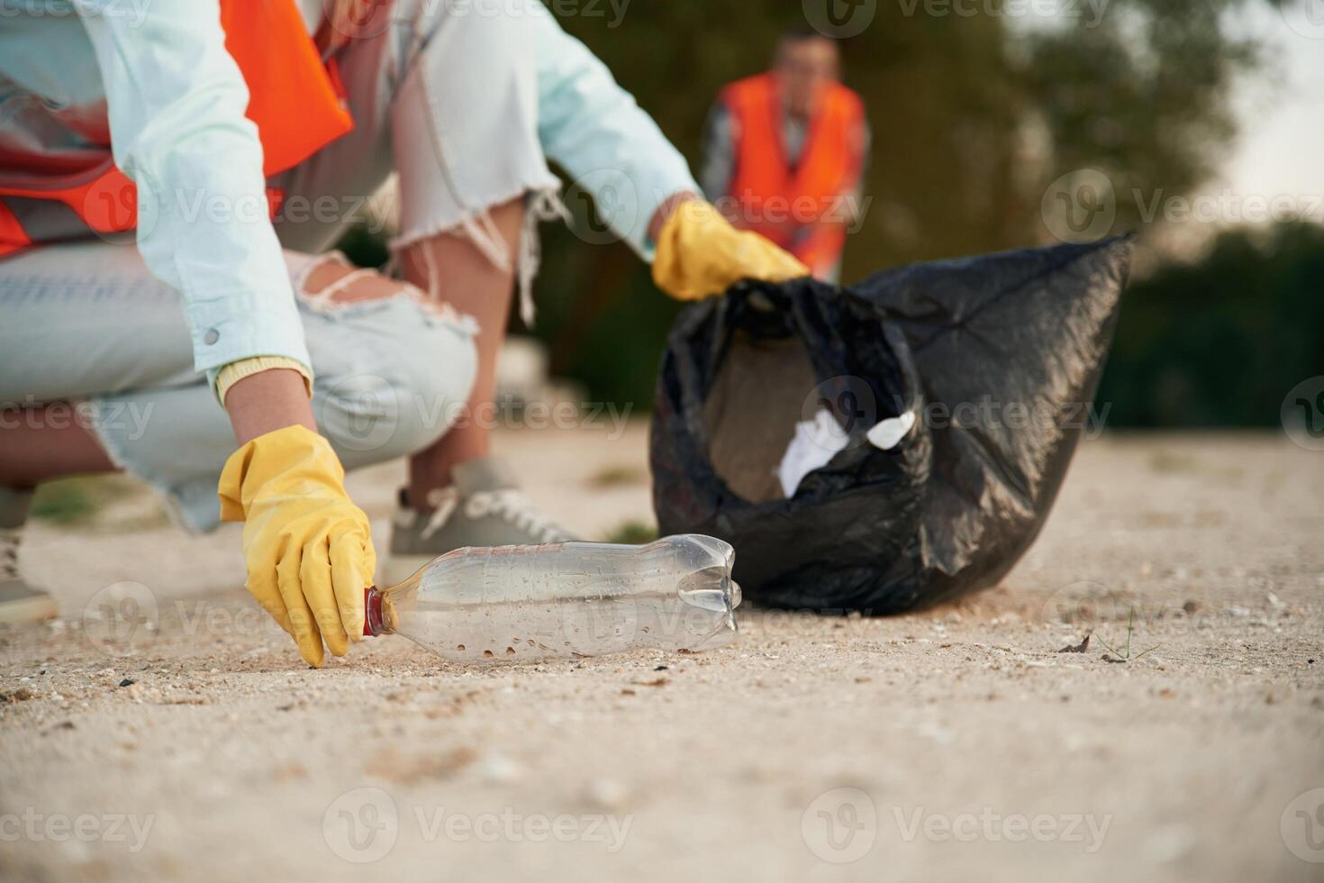 Picking ,up t,he bottle. A volunteers collects garbage on a muddy beach photo