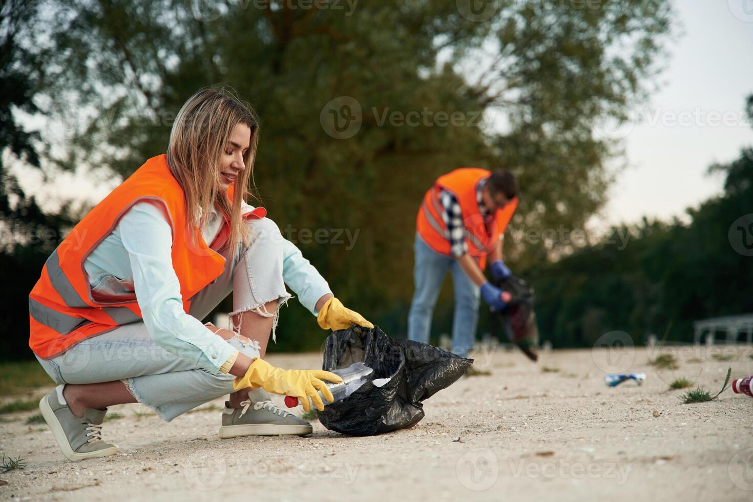 Picking ,up the bottle.. A volunteers collects garbage on a muddy beach photo