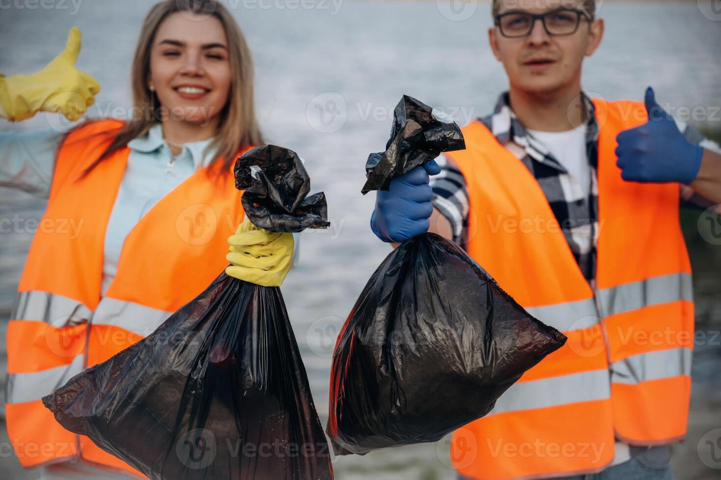 Showing ,fingers up, smiling, finished. A volunteers collects garbage on a muddy beach photo