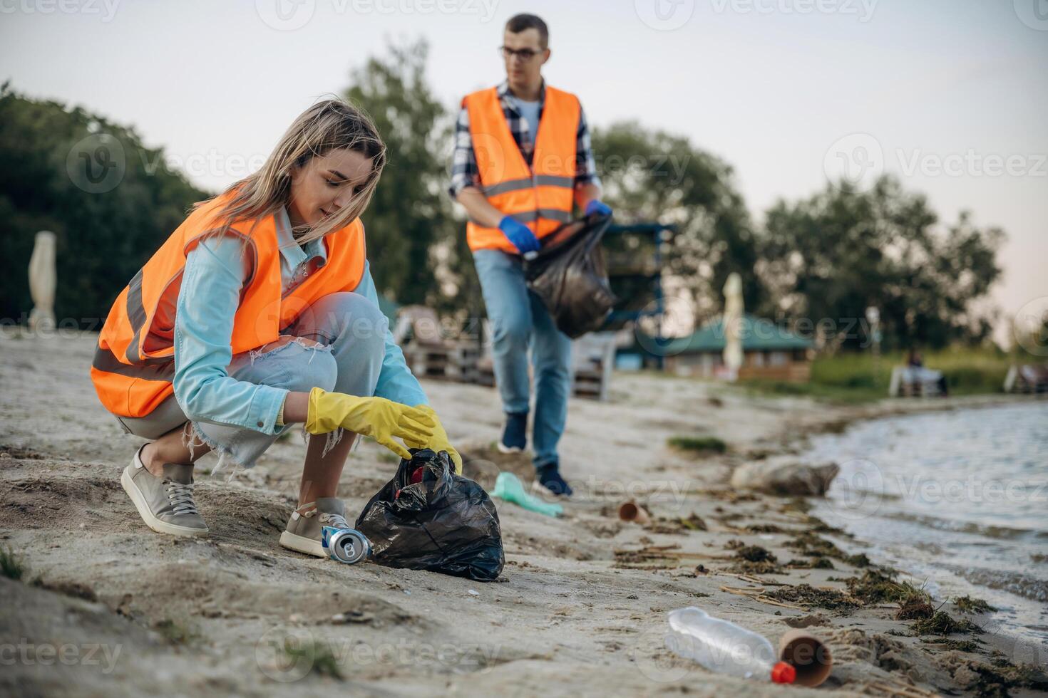 On ,the, shore. A volunteers collects garbage on a muddy beach photo