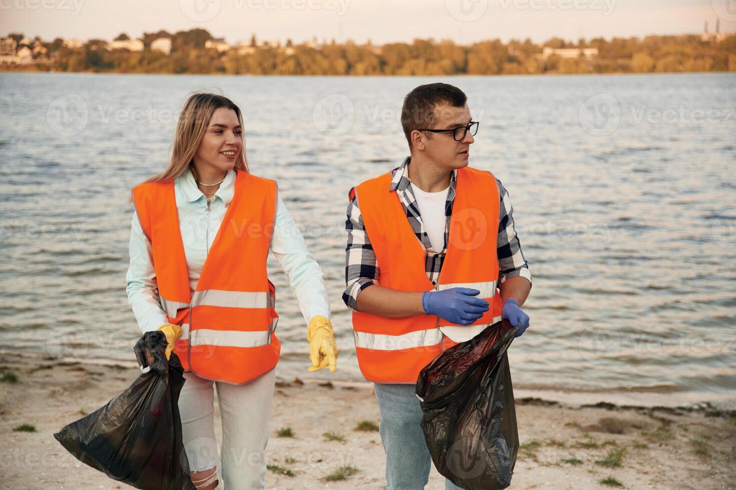 A ,volunteers, collects garbage on a muddy beach photo