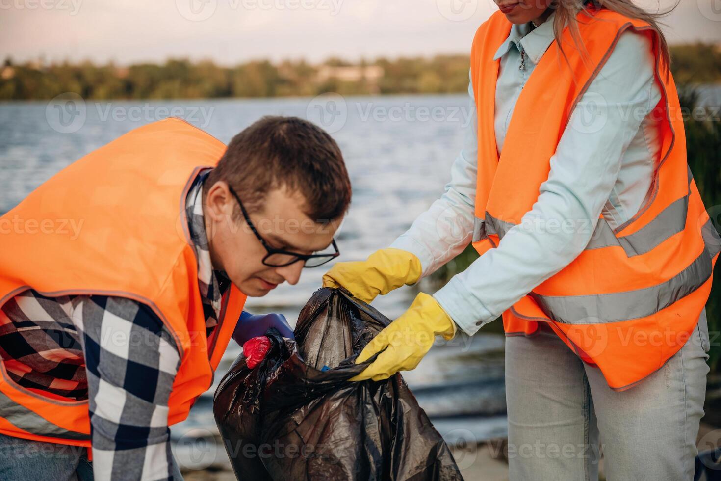With trash ,,bags. A volunteers collects garbage on a muddy beach photo