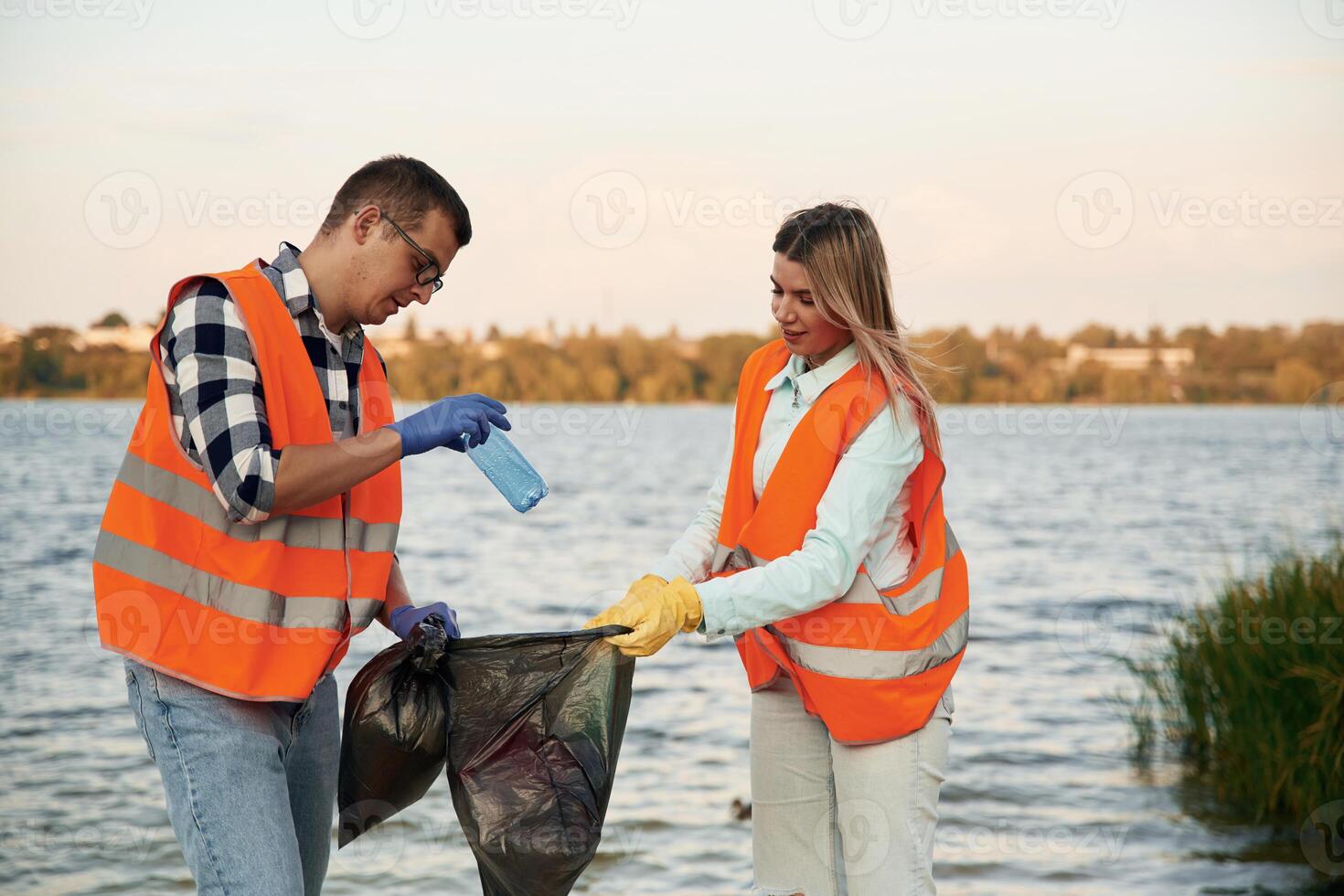 With ,trash, bags. A volunteers collects garbage on a muddy beach photo