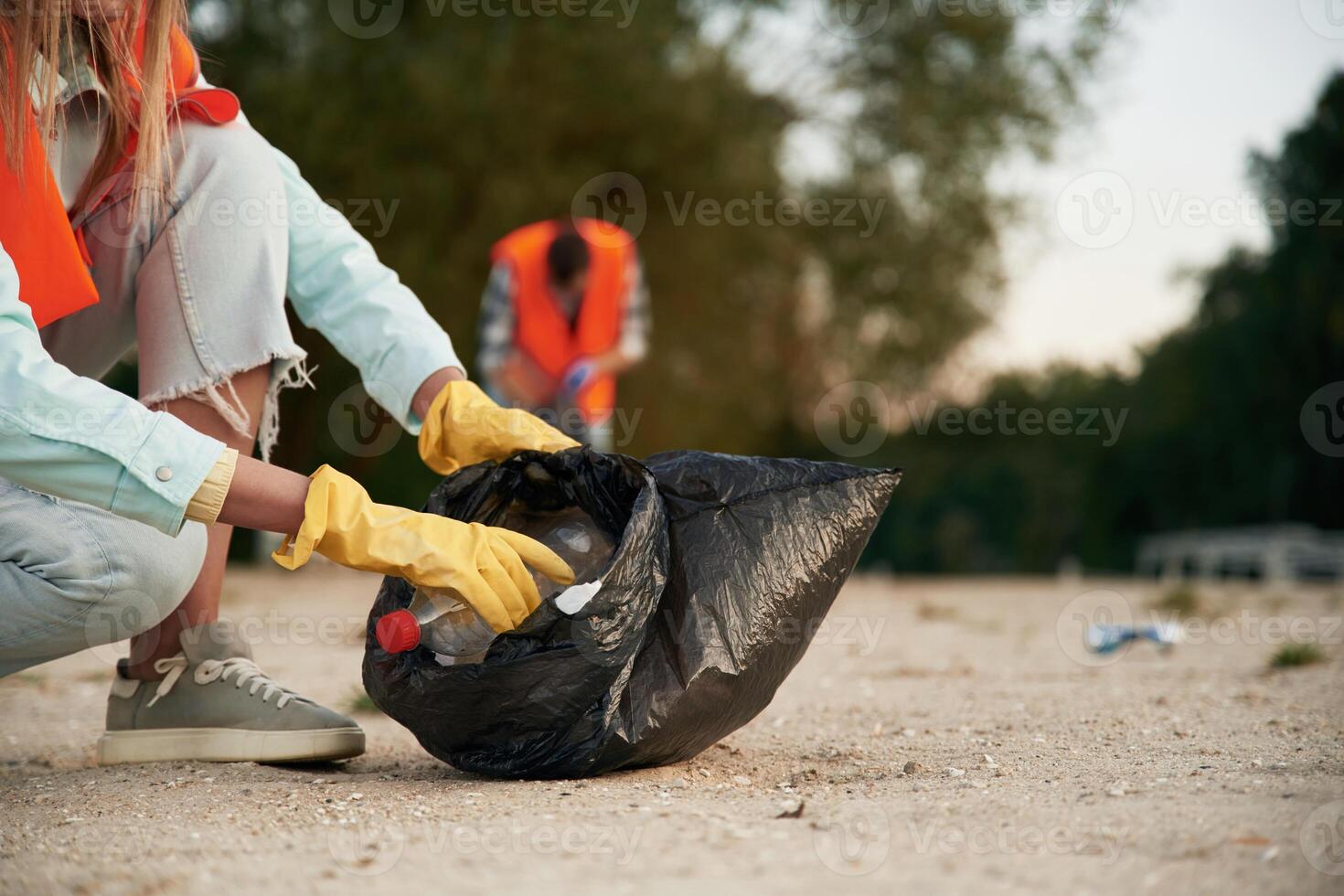 Picking up, the bottle. A volunteers collects garbage on a muddy beach photo