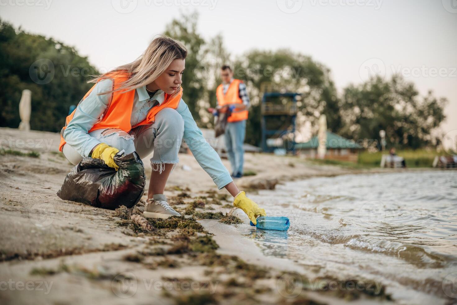 Picking, bottle from the water. A volunteers collects garbage on a muddy beach photo
