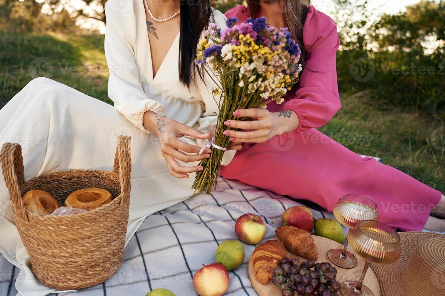 Fruits,, flowers and glasses of drink. Lesbian couple is together on the picnic in nature photo