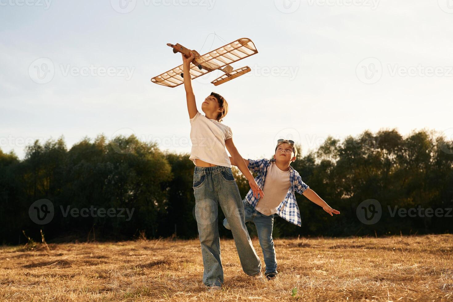 Having ,,fun. Boy and girl are playing with wooden toy plane on the field photo