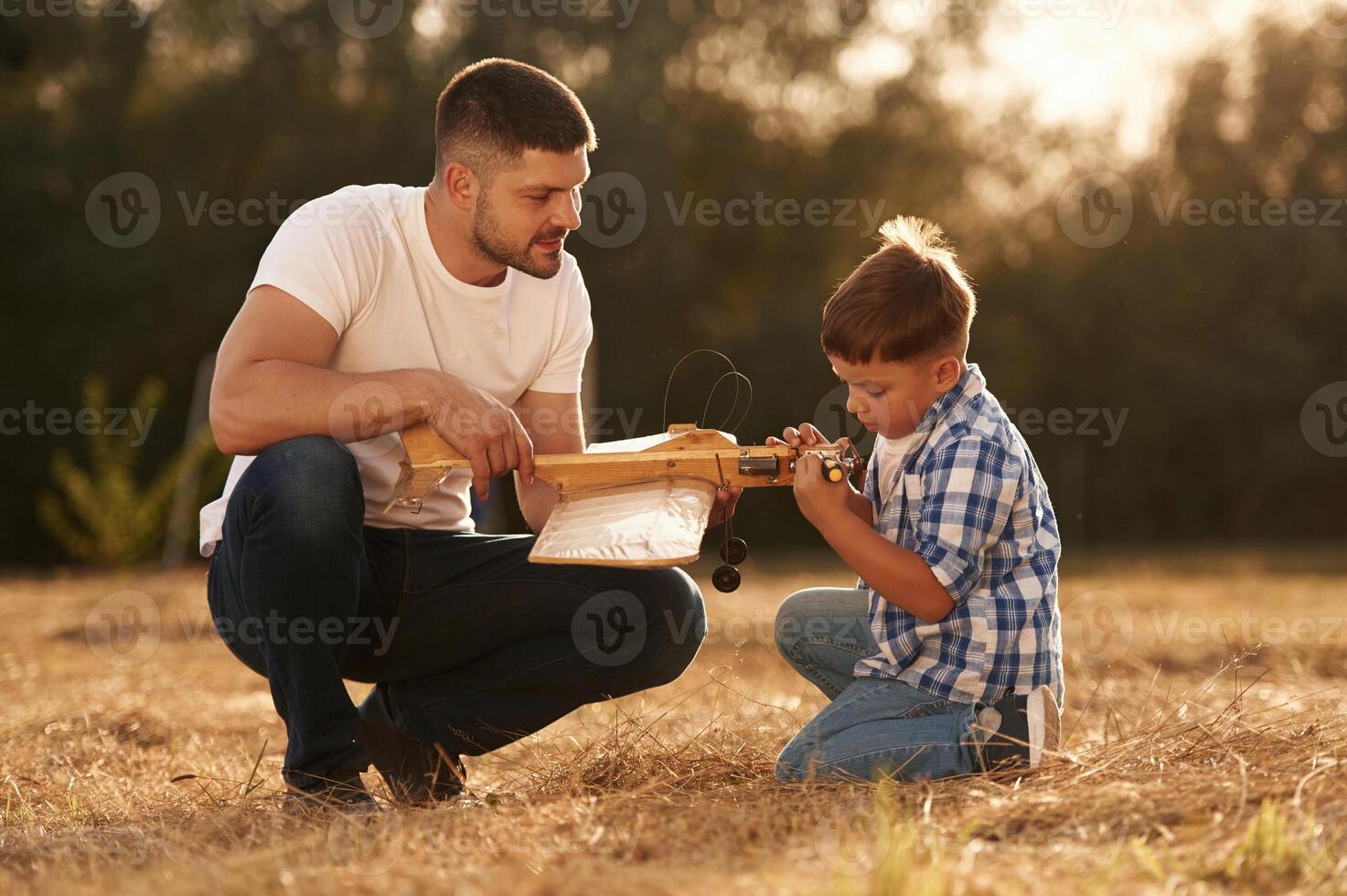 Handmade toy plane is broken, fixing it. Father and son are on the field photo