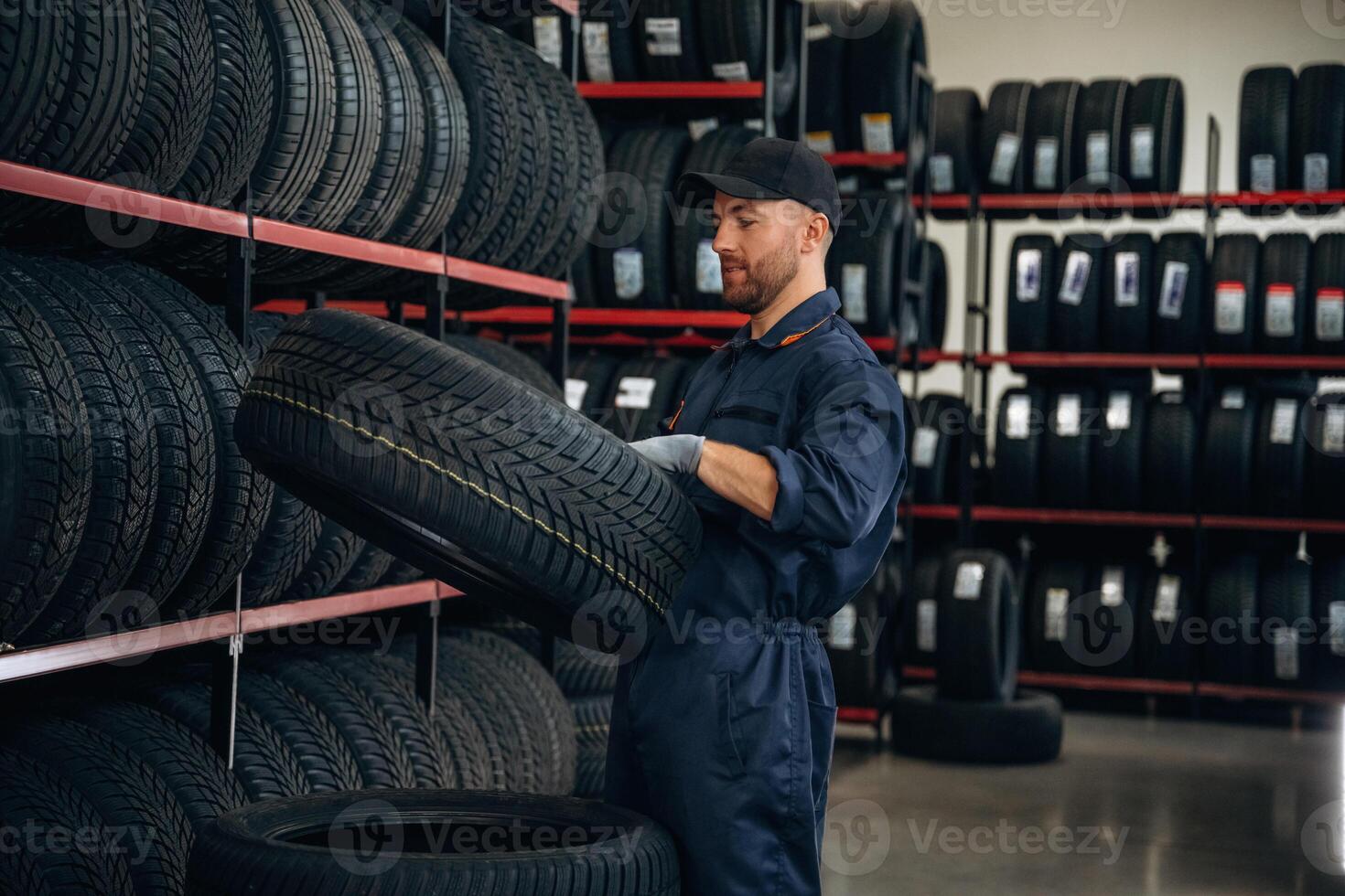 Holding the wheel., Man worker is maintenance station with tires photo