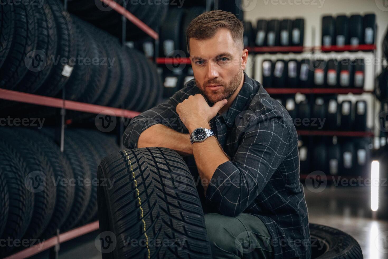 Thinking, sitting... Man worker is maintenance station with tires, wheels photo