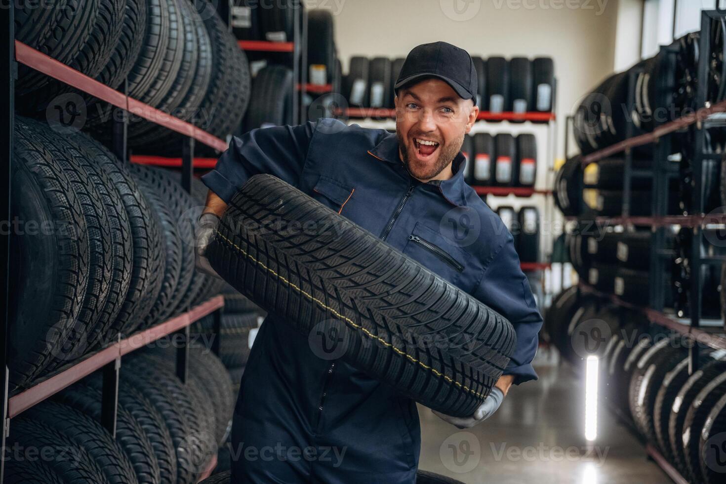 Holding, the,,,, wheel. Man worker is maintenance station with tires photo