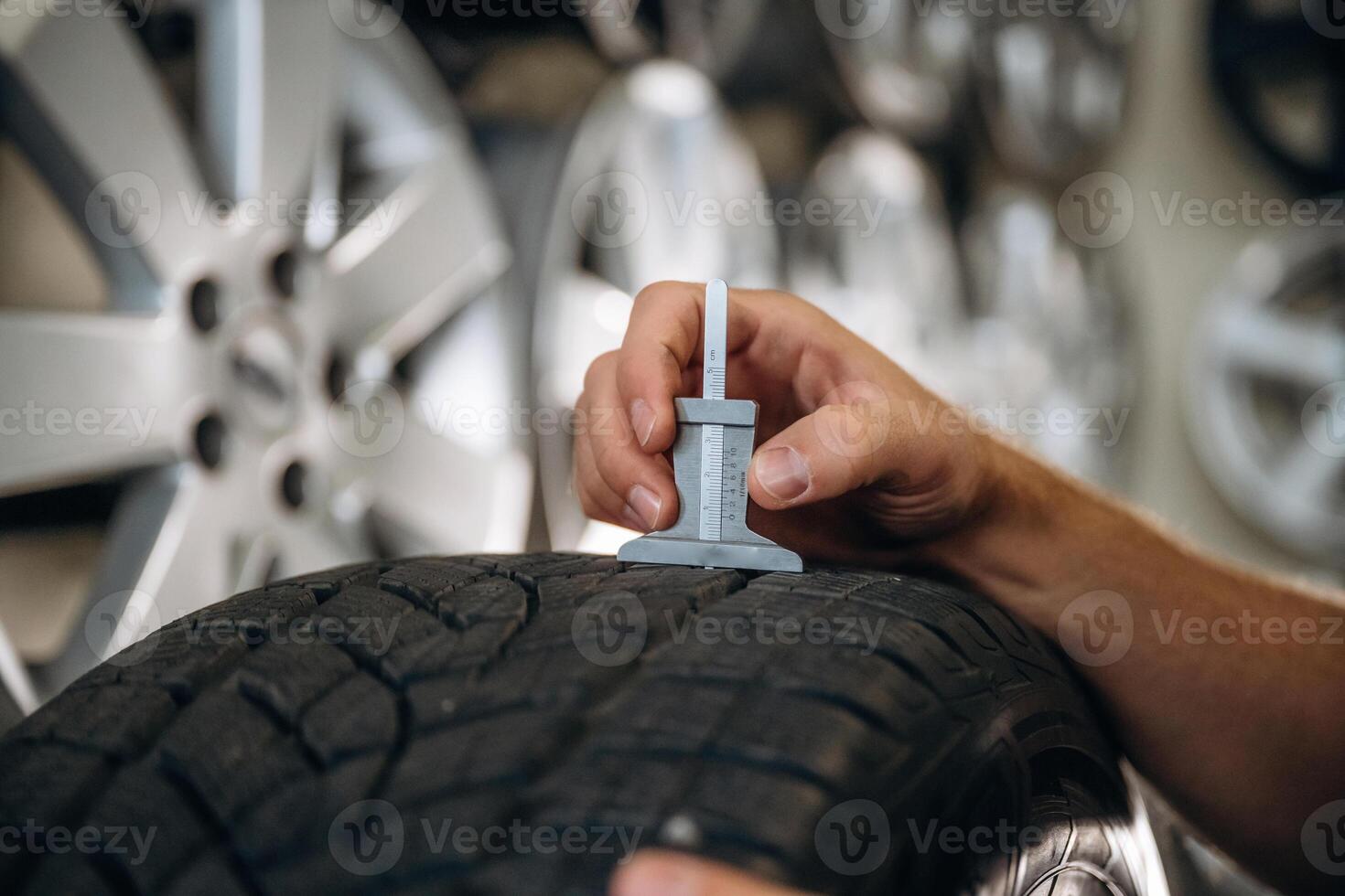 Tool in hand,,,, checking the quality. Man worker is maintenance station with tires, wheels photo