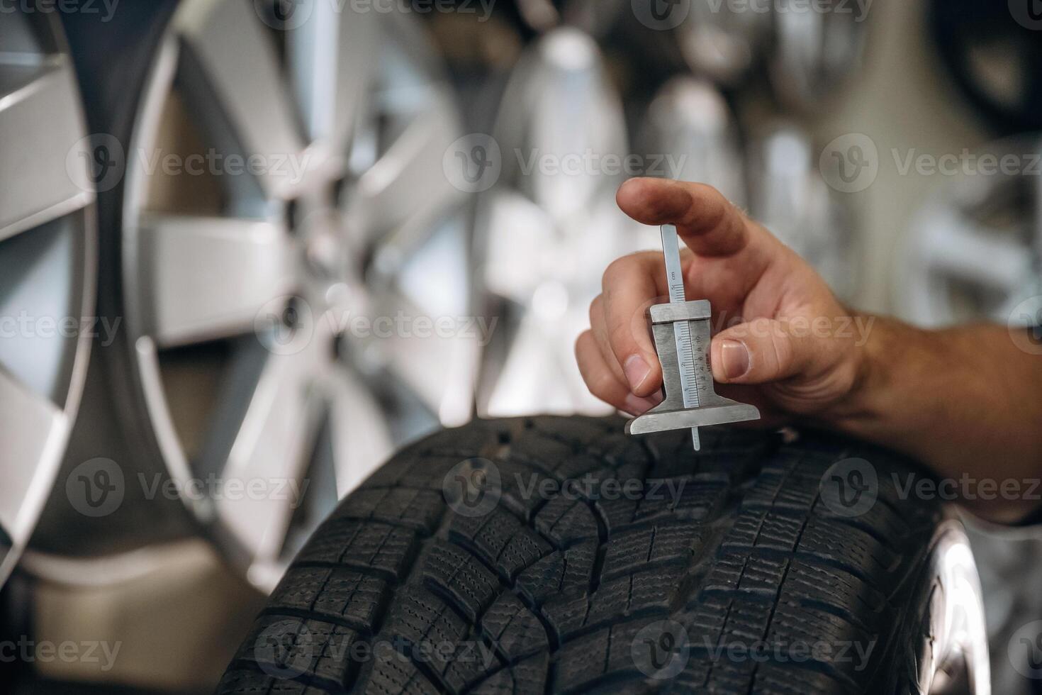 Employee is ,using ,,measuring tool. Man worker is maintenance station with tires, wheels photo