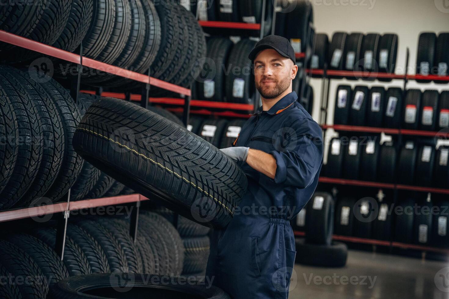 Holding, the ,wheel. Man worker is maintenance station with tires photo
