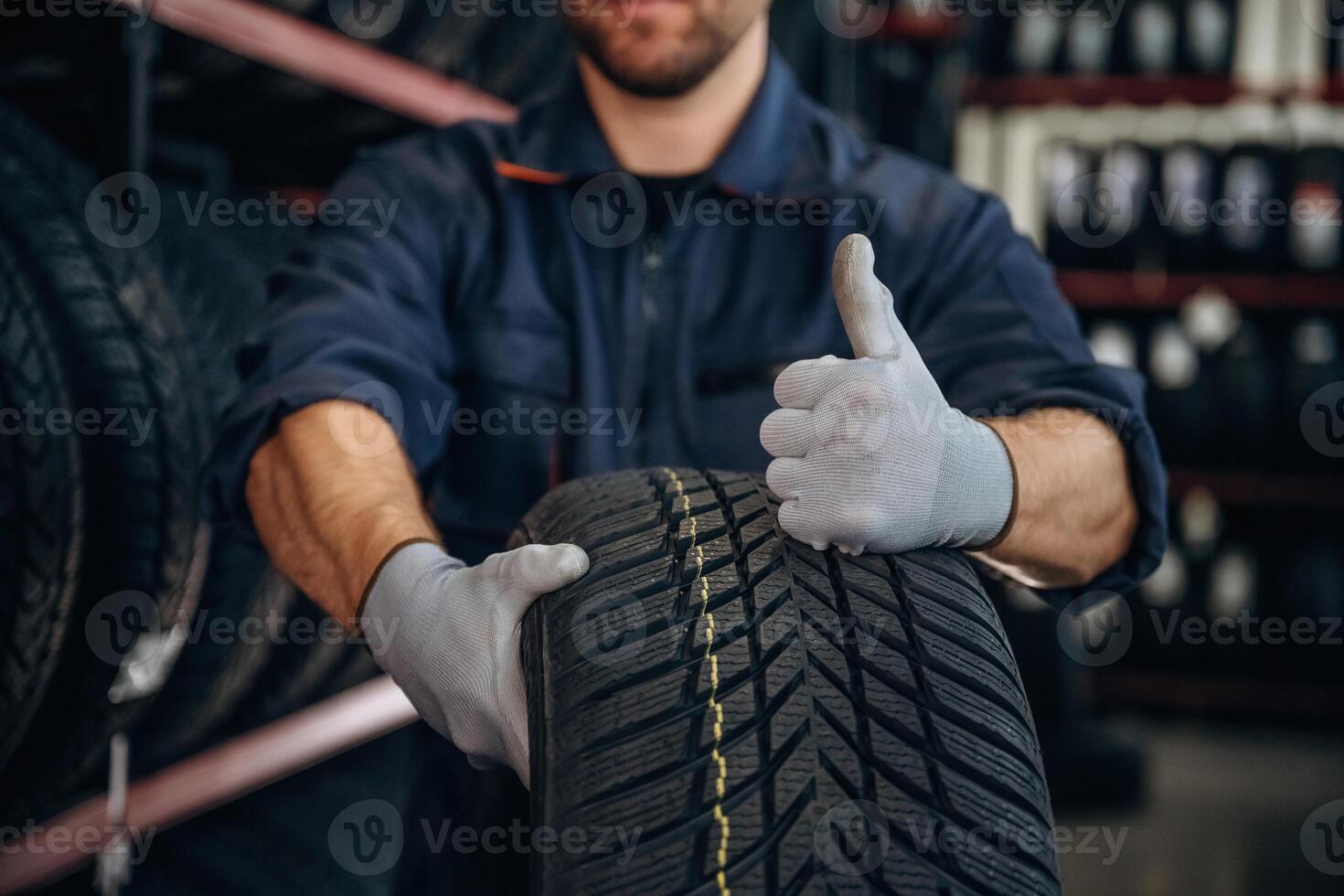 Focused close, up view, thumb up, holding a tire. Man worker is maintenance station with wheels photo