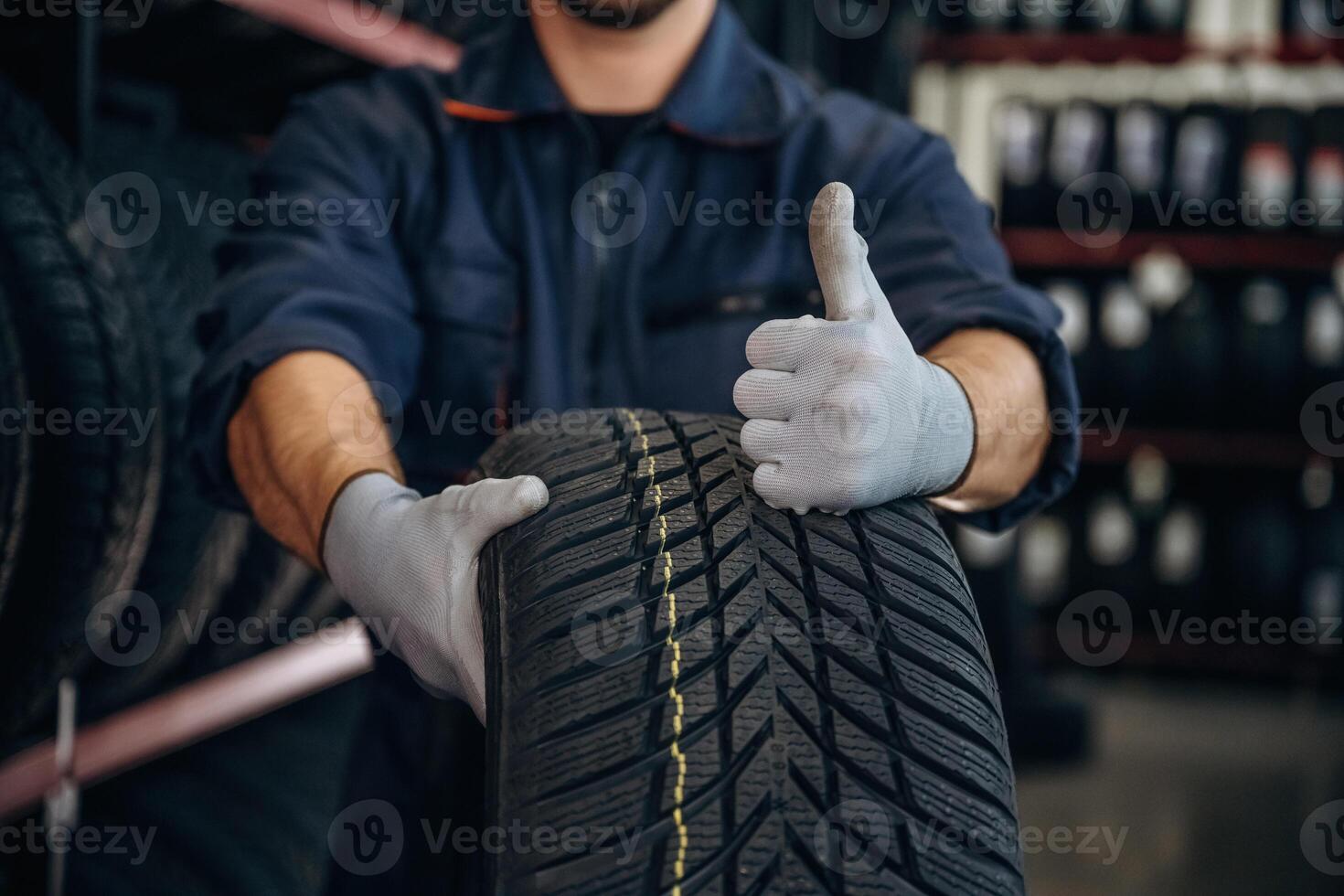 Focused ,close up view, thumb up, holding a tire. Man worker is maintenance station with wheels photo
