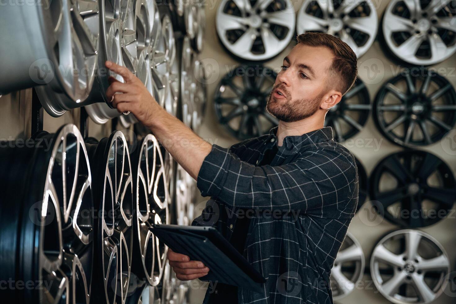 Manager is checking, the product, with digital tablet. Man worker is maintenance station with tires, wheels photo