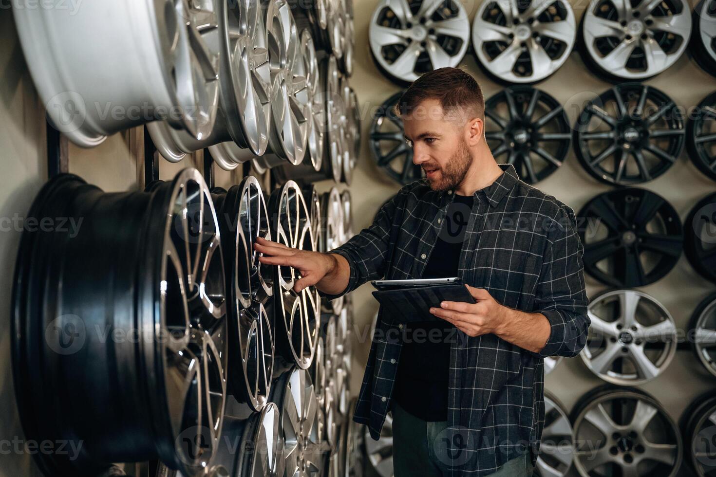 Manager, is checking the product, with digital tablet. Man worker is maintenance station with tires, wheels photo