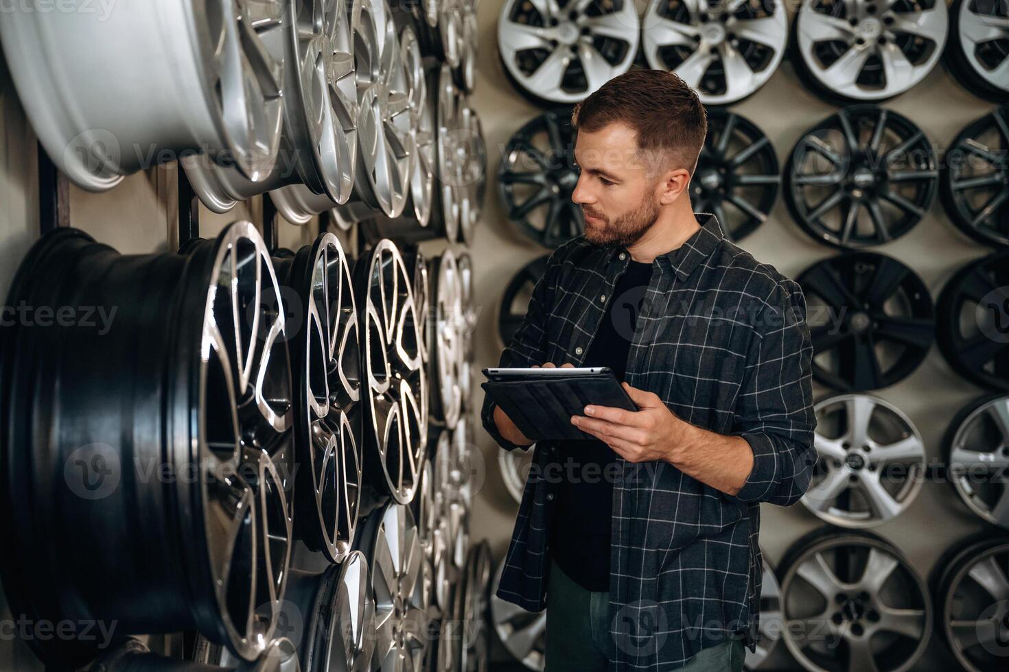 Manager, is ,checking the product, with digital tablet. Man worker is maintenance station with tires, wheels photo