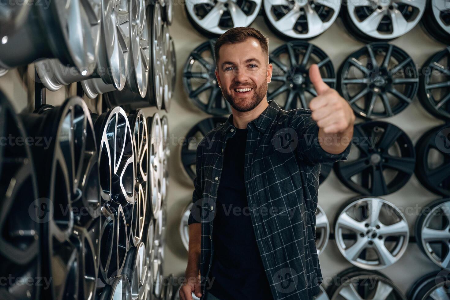 Thumb, up, gesture. Man worker is maintenance station with tires, wheels photo