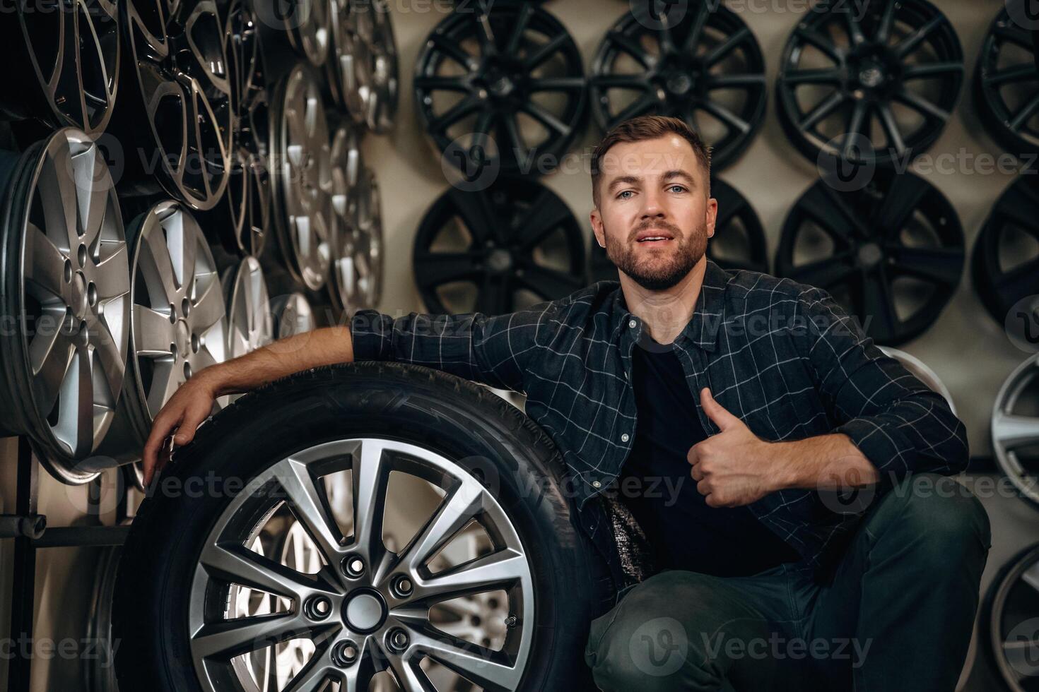 Thumb,, up, gesture. Man worker is maintenance station with tires, wheels photo