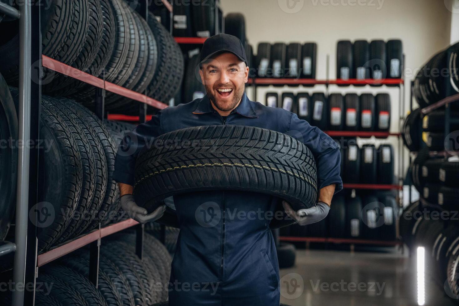 Holding ,the wheel. Man worker is maintenance station with tires photo